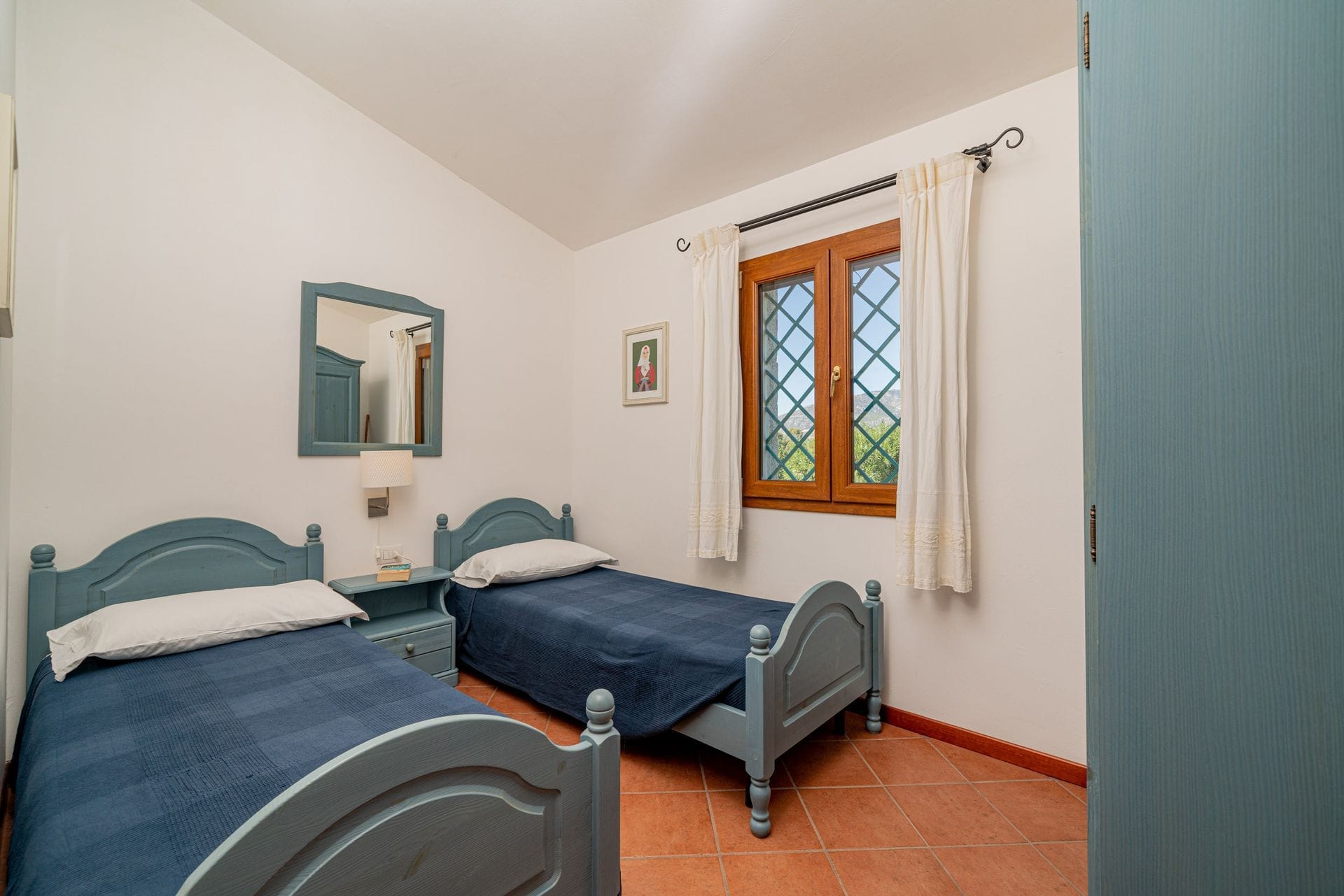 I nostri appartamenti con due camere da letto sono arredati in stile mediterraneo e hanno un layout simile tra loro. Ogni appartamento dispone di una veranda esterna coperta e ombreggiata che si affaccia sul giardino, di un soggiorno con zona pranzo e cucina, di due camere da letto di cui una matrimoniale e una a due letti e di un bagno.