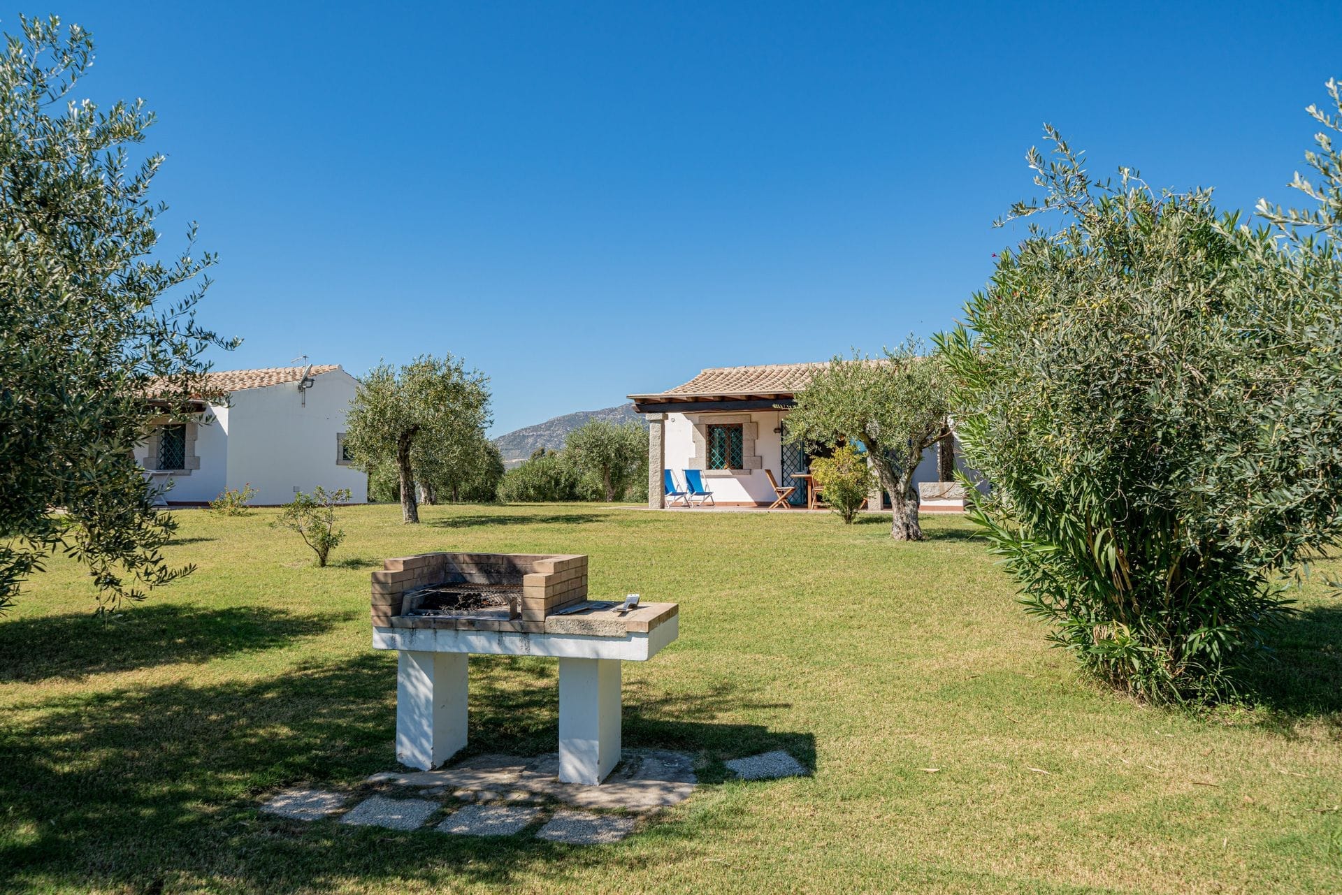 I nostri appartamenti con due camere da letto sono arredati in stile mediterraneo e hanno un layout simile tra loro. Ogni appartamento dispone di una veranda esterna coperta e ombreggiata che si affaccia sul giardino, di un soggiorno con zona pranzo e cucina, di due camere da letto di cui una matrimoniale e una a due letti e di un bagno.