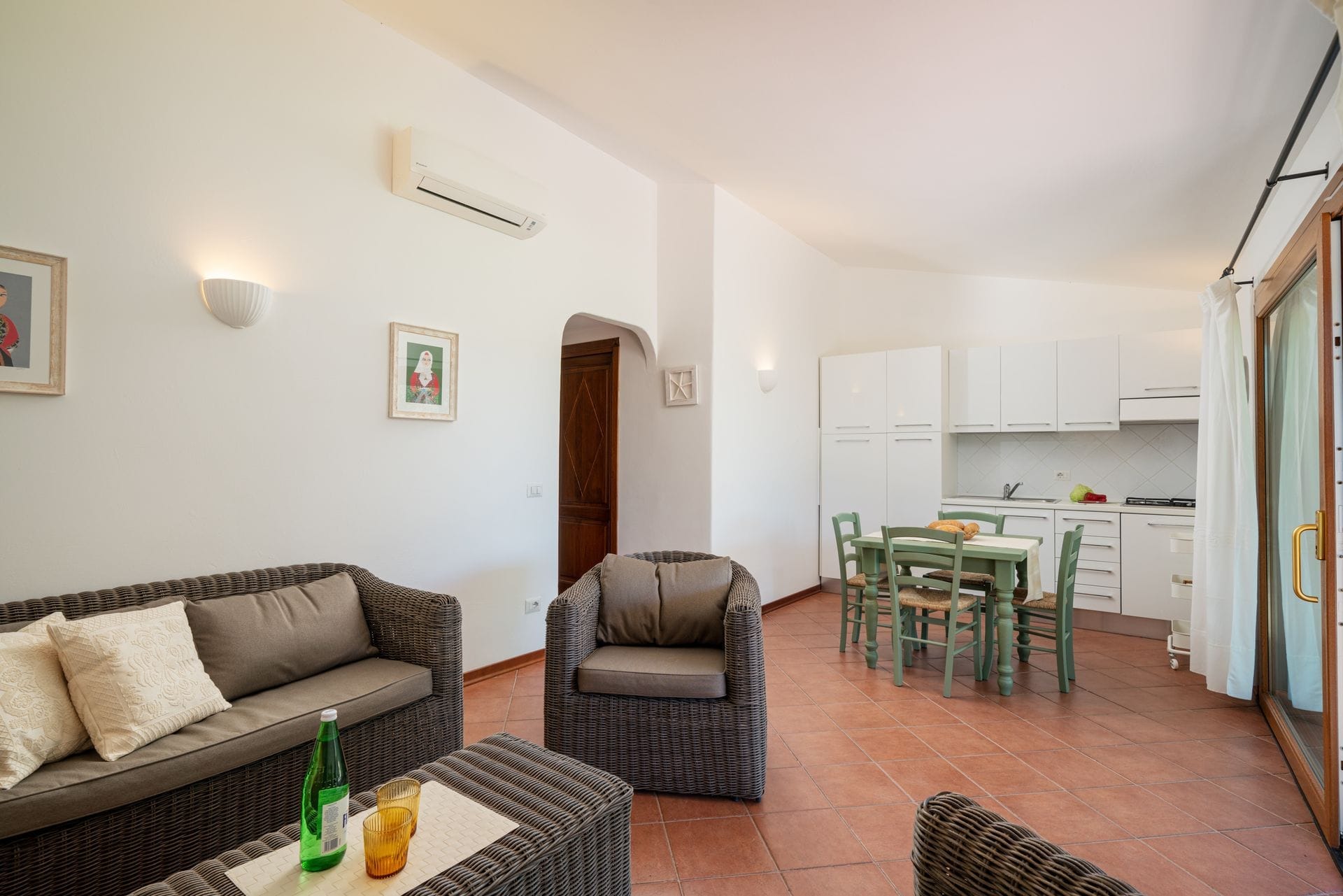 I nostri appartamenti con due camere da letto sono arredati in stile mediterraneo e hanno un layout simile tra loro. Ogni appartamento dispone di una veranda esterna coperta e ombreggiata che si affaccia sul giardino, di un soggiorno con zona pranzo e cucina, di due camere da letto di cui una matrimoniale e una a due letti e di un bagno.
