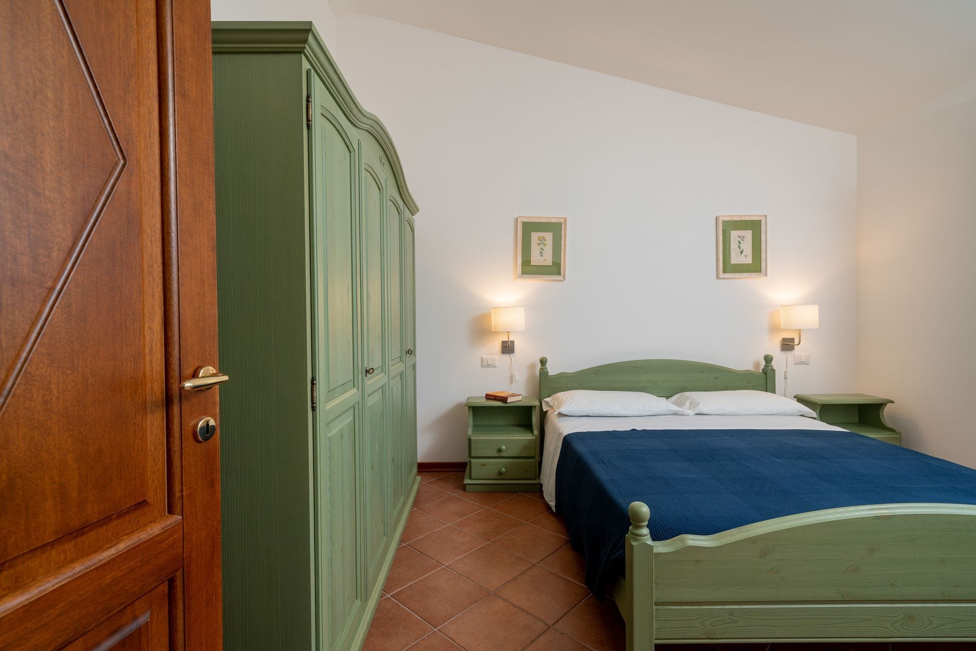 I nostri appartamenti con due camere da letto sono arredati in stile mediterraneo e hanno un layout simile tra loro. Ogni appartamento dispone di una veranda esterna coperta e ombreggiata che si affaccia sul giardino, di un soggiorno con zona pranzo e cucina, di due camere da letto di cui una matrimoniale e una a due letti e di un bagno.
